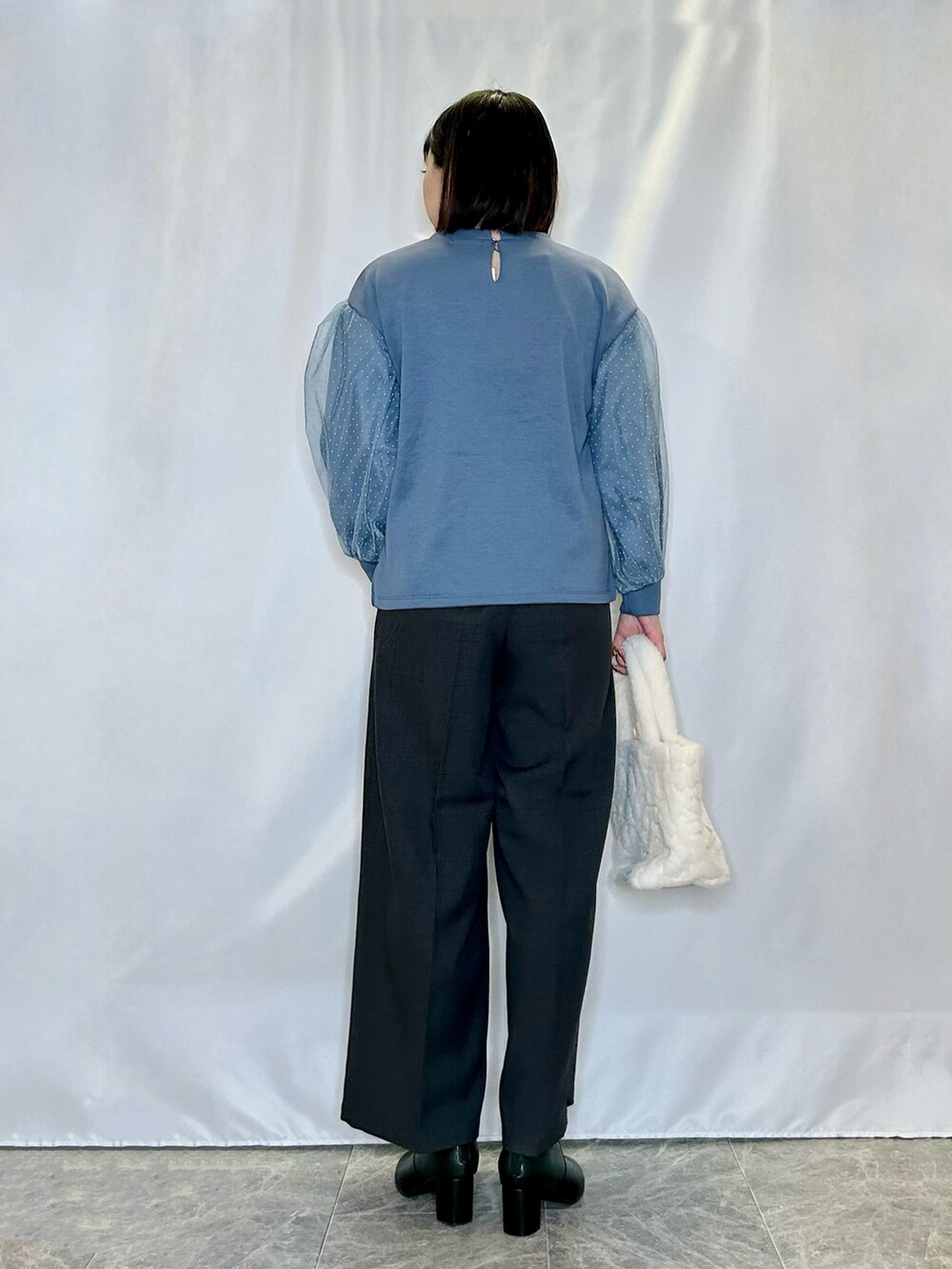 ブルー系のTシャツ/カットソー、ベージュ系のトートバッグ、ブラック系のブーツを着用したレディースの冬コーディネートの3枚目の写真