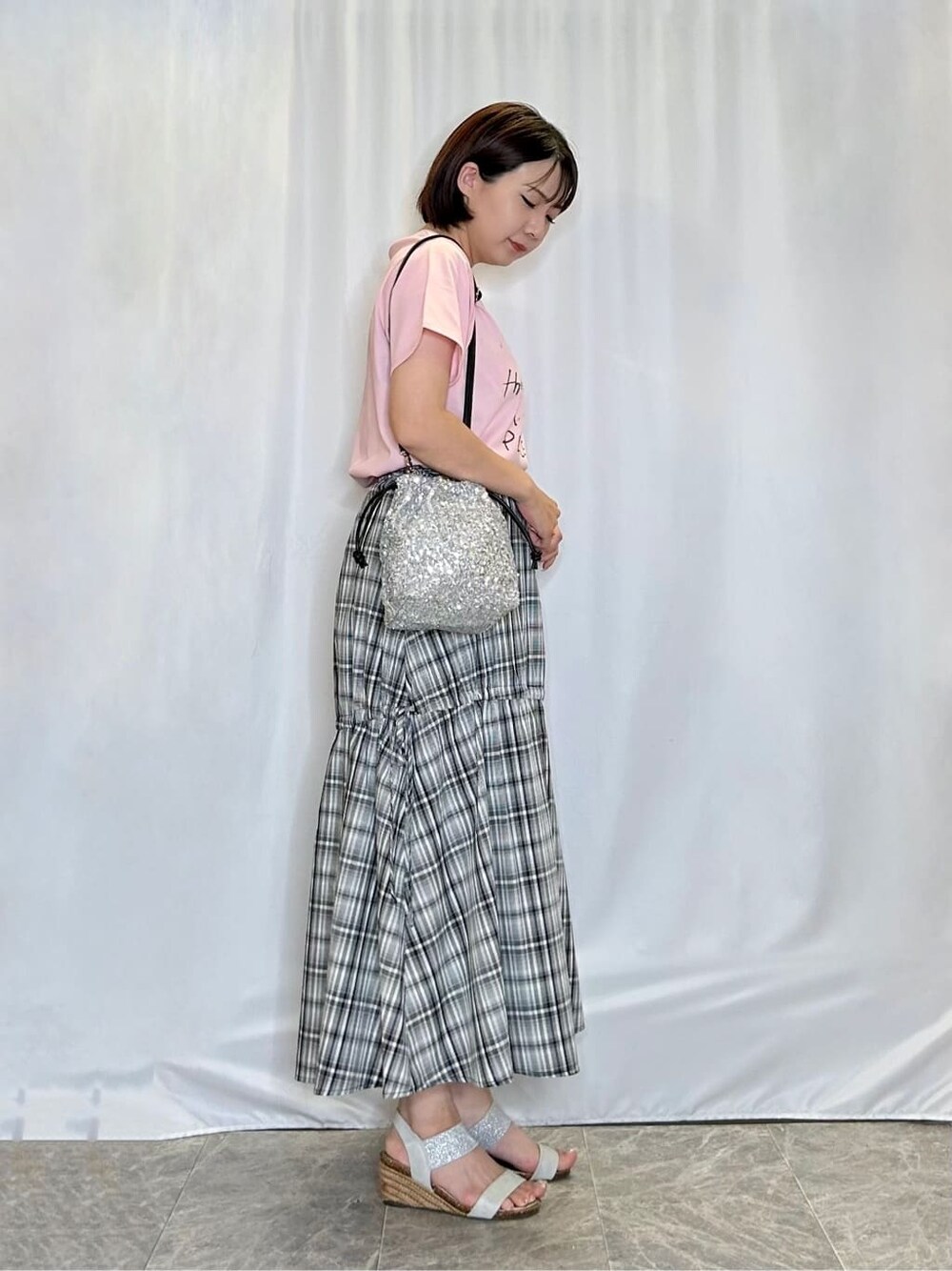 ピンク系のTシャツ/カットソー、ブラック系のスカート、シルバー系のサンダルを着用したレディースの夏コーディネートの2枚目の写真