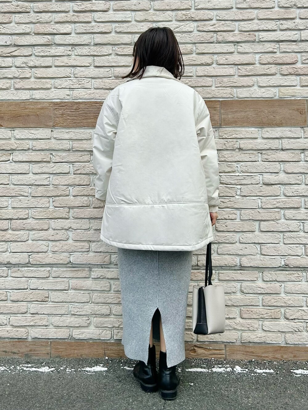 ホワイト系のその他アウター、グレー系のニット/セーター、グレー系のスカートを着用したレディースの冬コーディネートの3枚目の写真