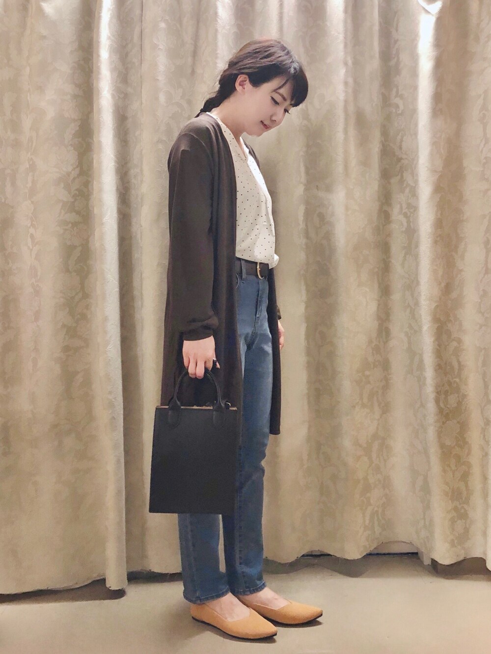 ブルー系のデニムパンツ、イエロー系のパンプス、ブラック系のショルダーバッグを着用したレディースの秋コーディネートの2枚目の写真