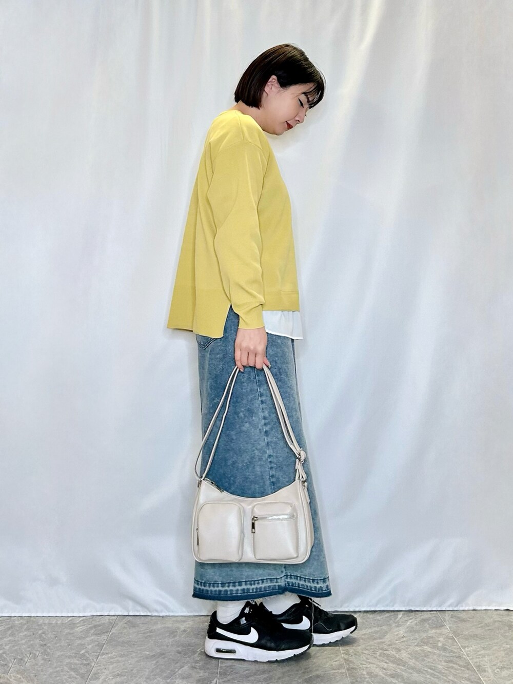 ブルー系のデニムスカート、グレー系のショルダーバッグ、イエロー系のニット/セーターを着用したレディースの冬コーディネートの2枚目の写真