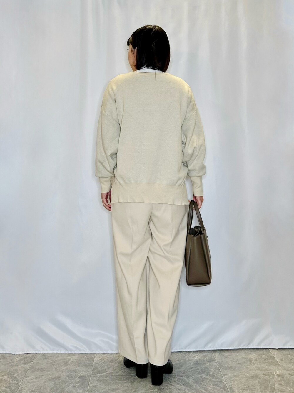 ホワイト系のTシャツ/カットソー、ホワイト系のニット/セーター、ブラック系のブーツを着用したレディースの冬コーディネートの3枚目の写真