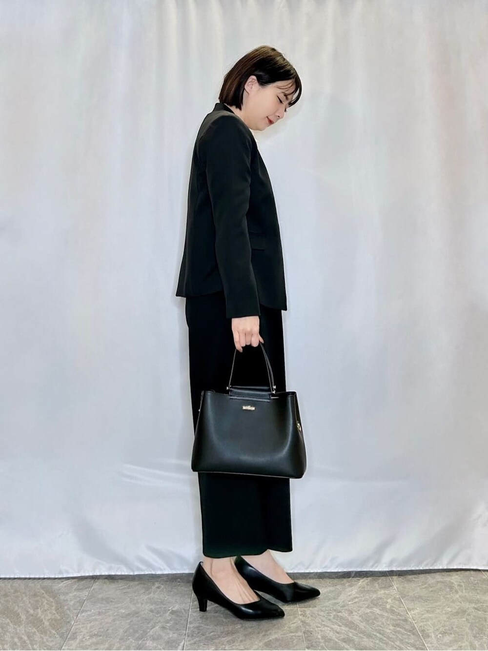 ブラック系のノーカラージャケット、ホワイト系のシャツ/ブラウス、ブラック系のその他パンツを着用したレディースの冬コーディネートの2枚目の写真