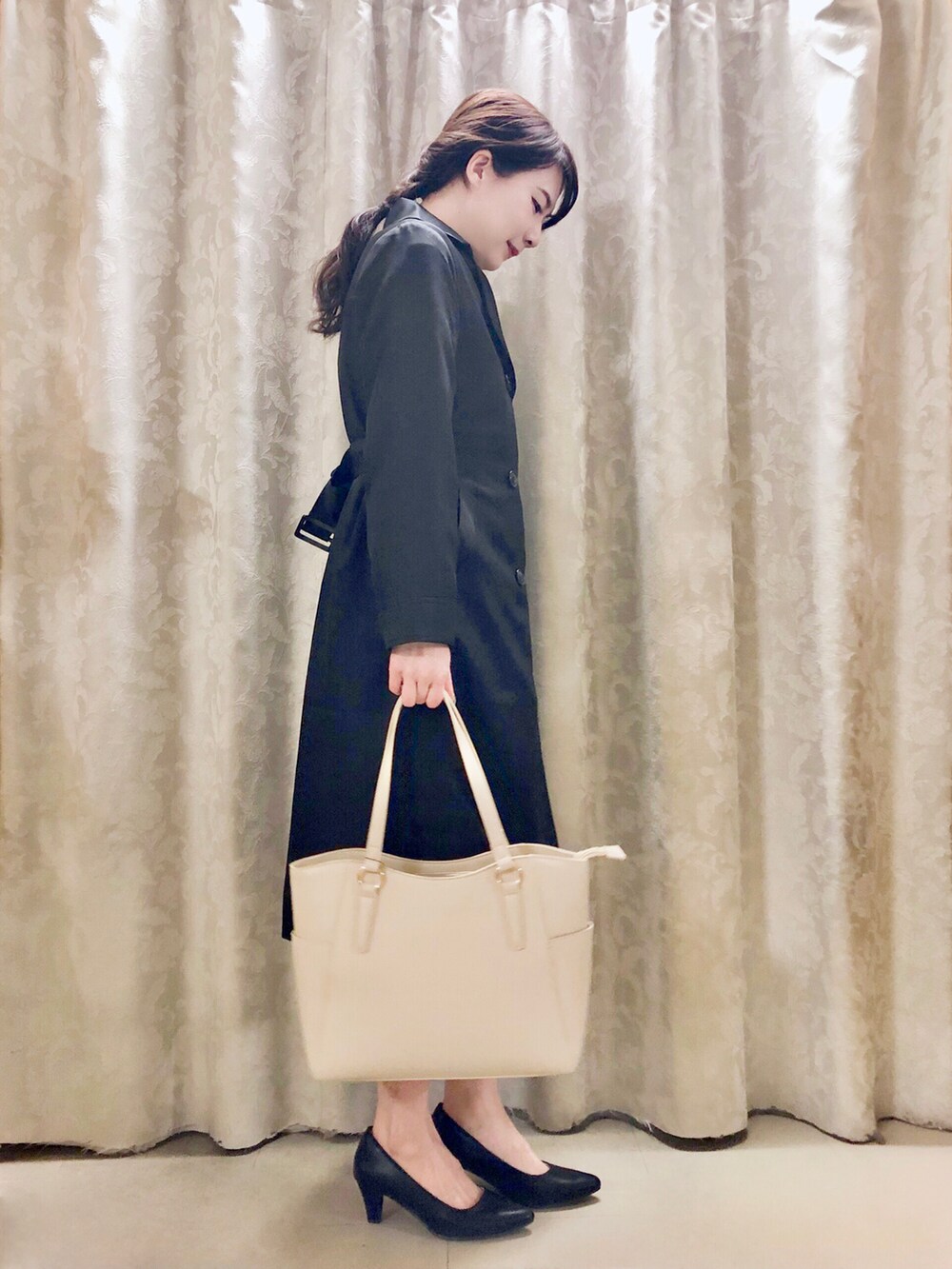 ホワイト系のトートバッグ、ブラック系のパンプス、ブラック系のトレンチコートを着用したレディースの春コーディネートの2枚目の写真