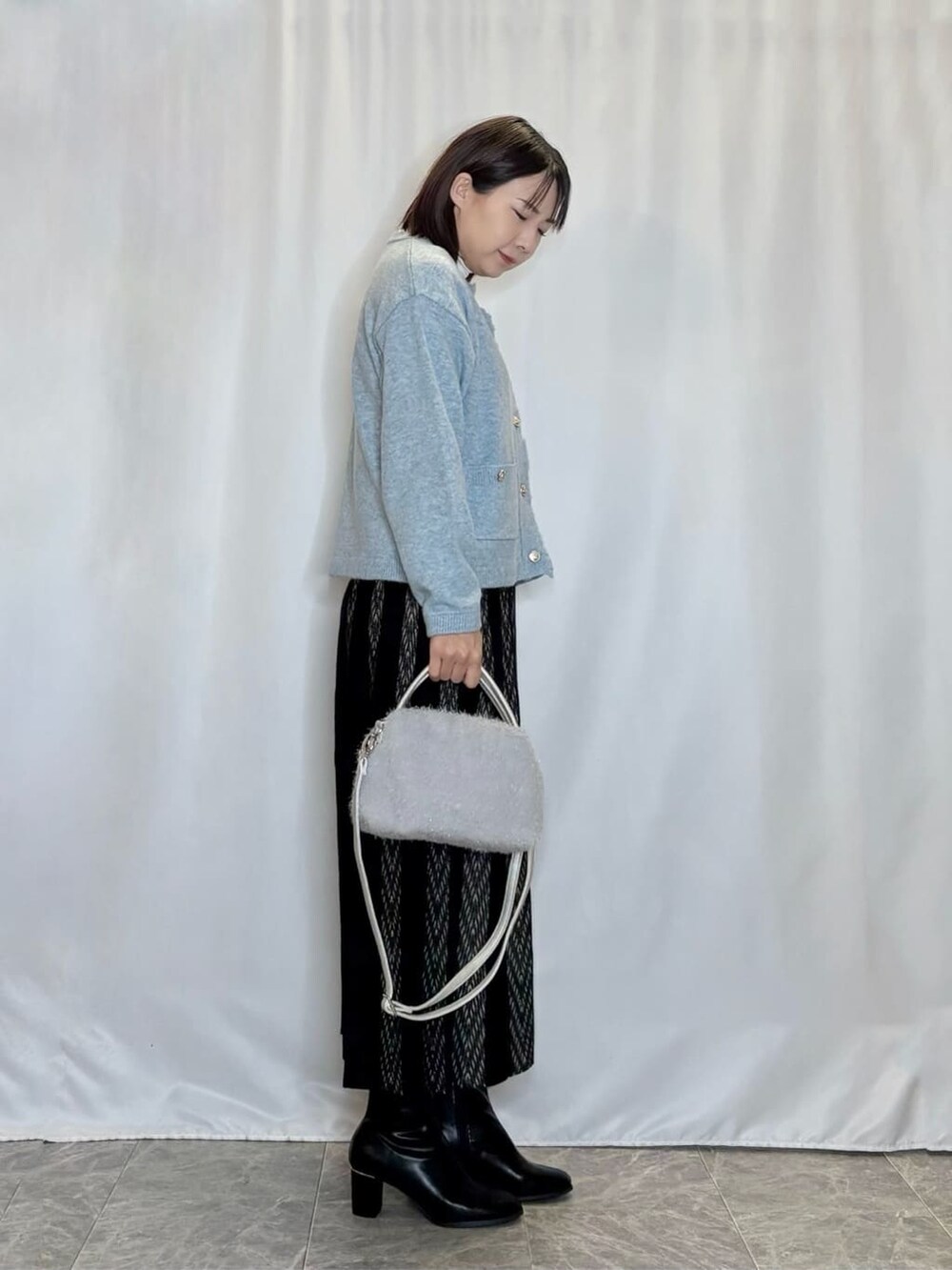 ブルー系のカーディガン/ボレロ、ホワイト系のTシャツ/カットソー、ブラック系のスカートを着用したレディースの秋コーディネートの2枚目の写真