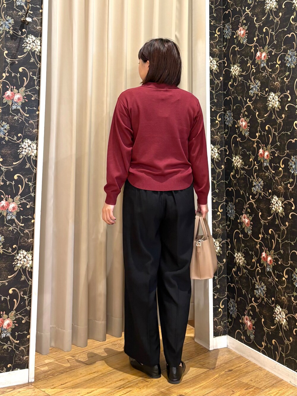レッド系のニット/セーター、ブラック系のその他パンツ、ベージュ系のトートバッグを着用したレディースの秋コーディネートの3枚目の写真