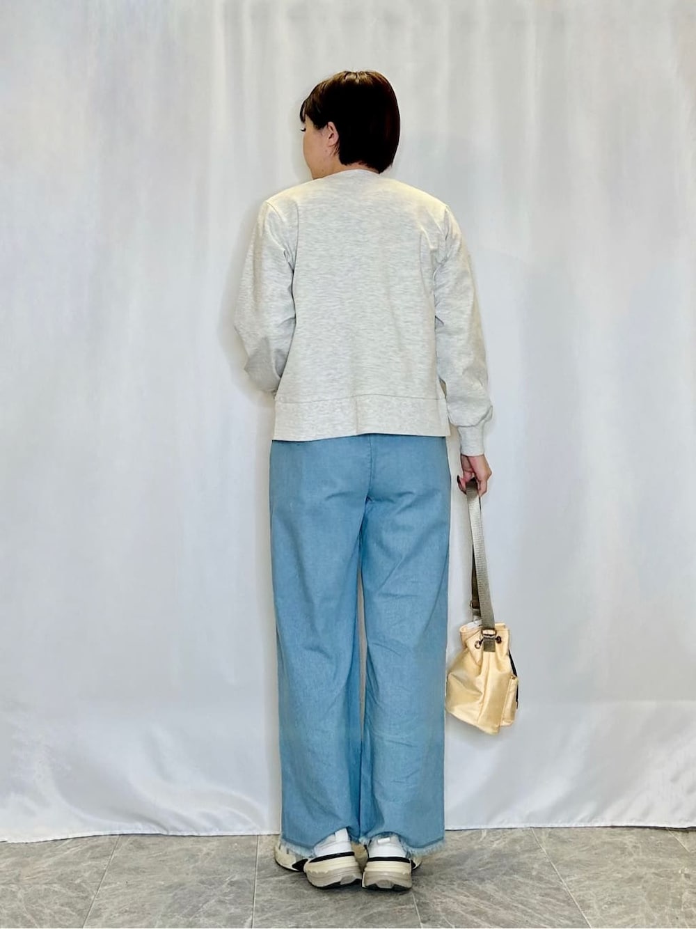 グレー系のカーディガン/ボレロ、ホワイト系のTシャツ/カットソー、ブルー系のデニムパンツを着用したレディースの春コーディネートの3枚目の写真