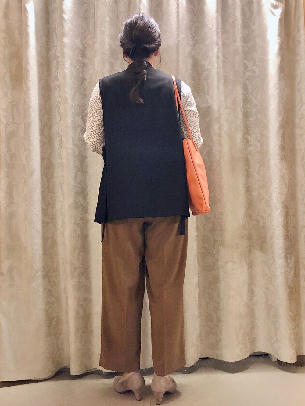 オレンジ系のトートバッグ、ベージュ系のパンプス、ベージュ系のパンツを着用したレディースの秋コーディネートの3枚目の写真