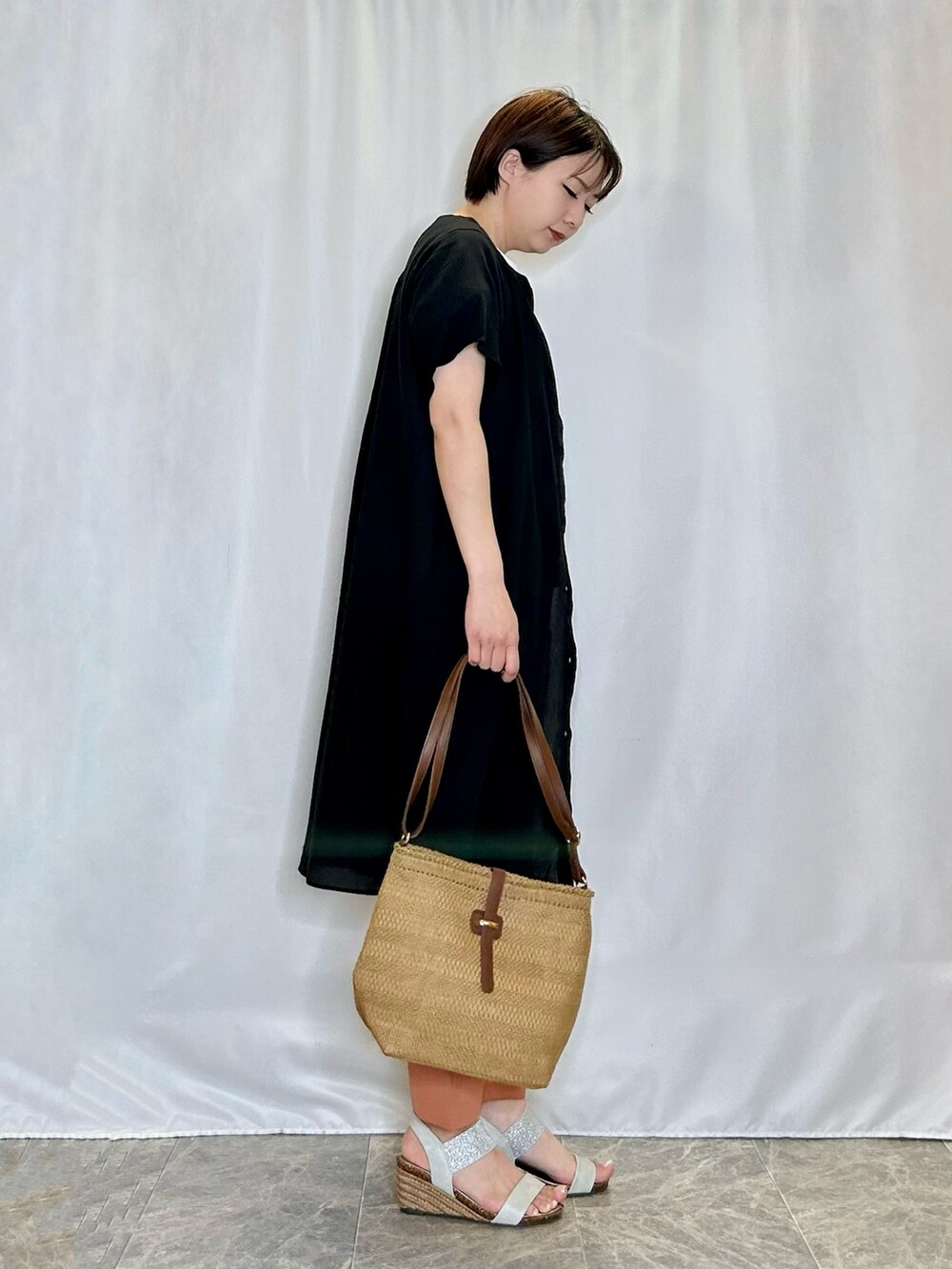 ブラック系のワンピース、ベージュ系のショルダーバッグ、シルバー系のサンダルを着用したレディースの春コーディネートの2枚目の写真