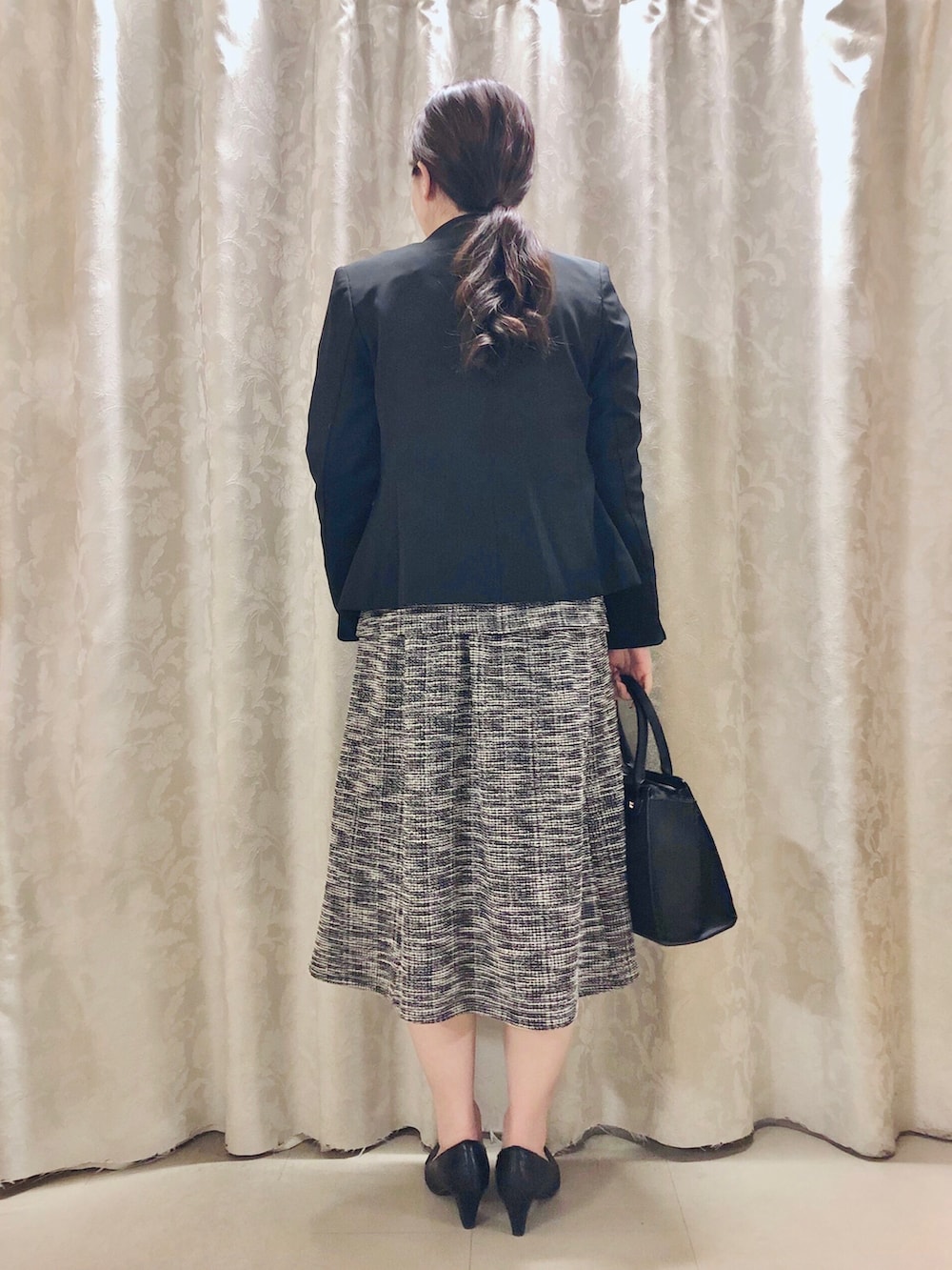 ブラック系のTシャツ/カットソー、ブラック系のスカート、ブラック系のパンプスを着用したレディースの春コーディネートの3枚目の写真