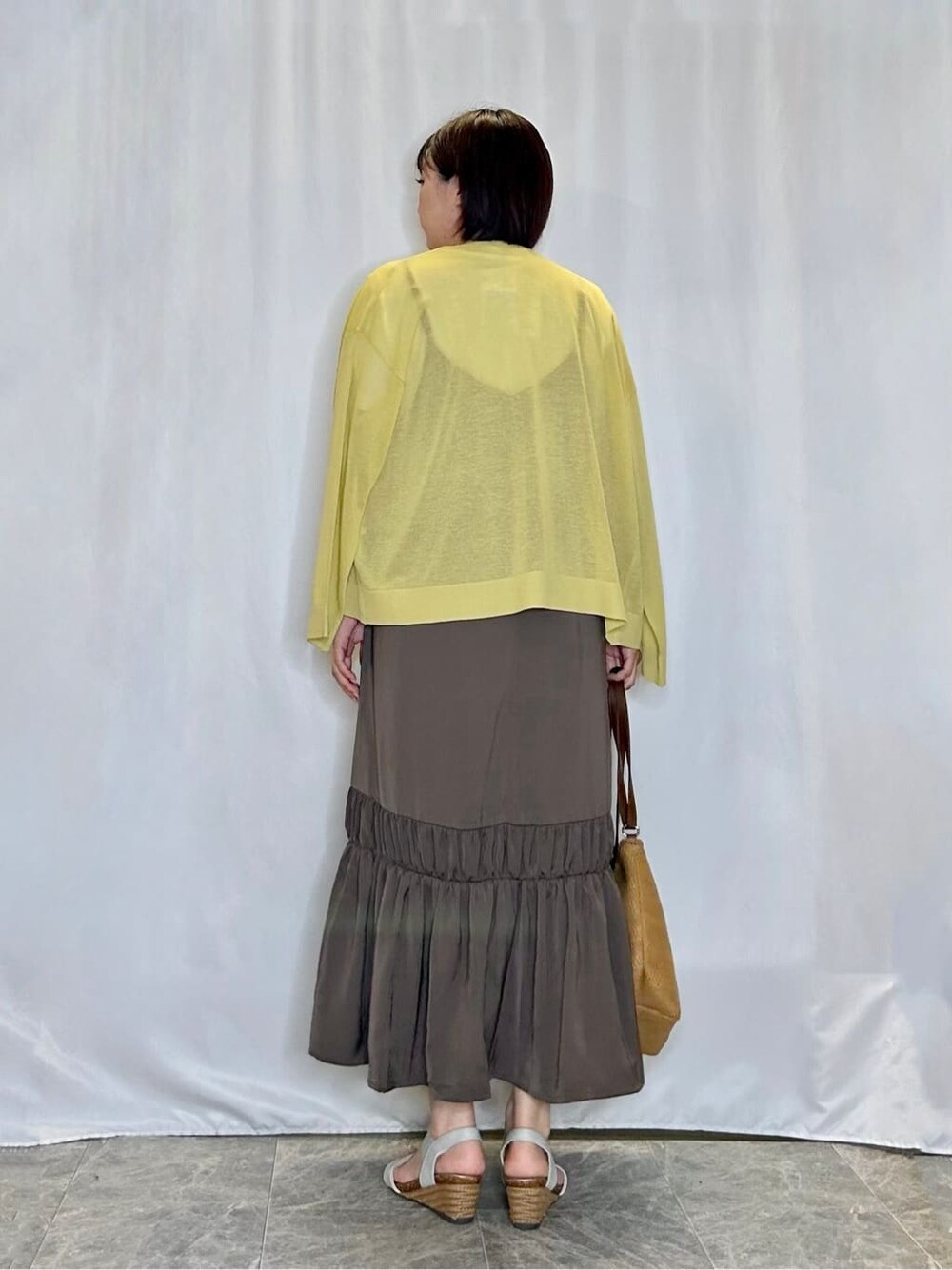 イエロー系のカーディガン/ボレロ、ブラウン系のワンピース、ホワイト系のTシャツ/カットソーを着用したレディースの夏コーディネートの3枚目の写真