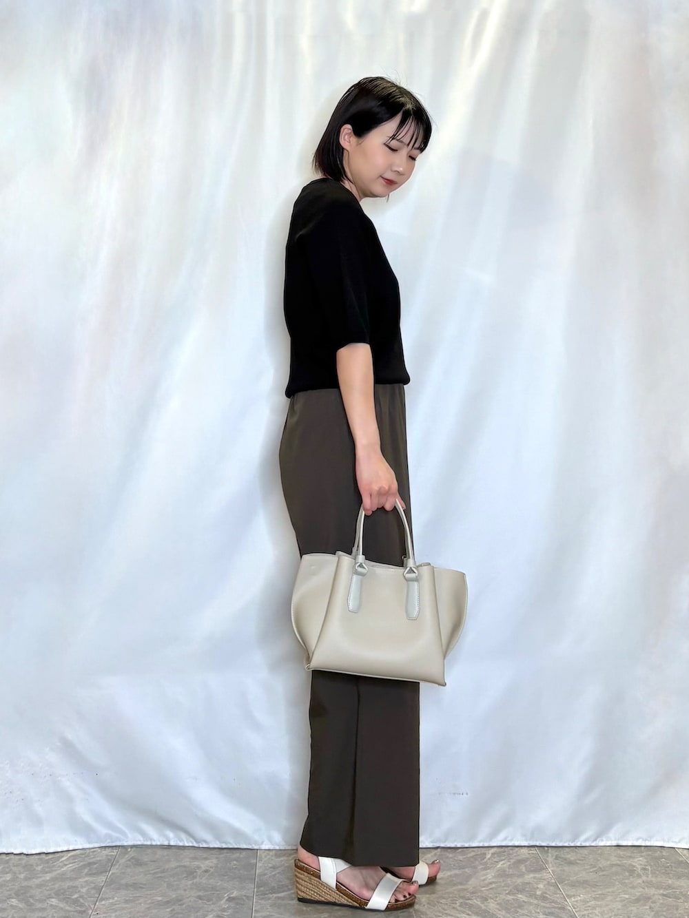ブラック系のニット/セーター、ブラウン系のその他パンツ、ホワイト系のサンダルを着用したレディースの夏コーディネートの2枚目の写真