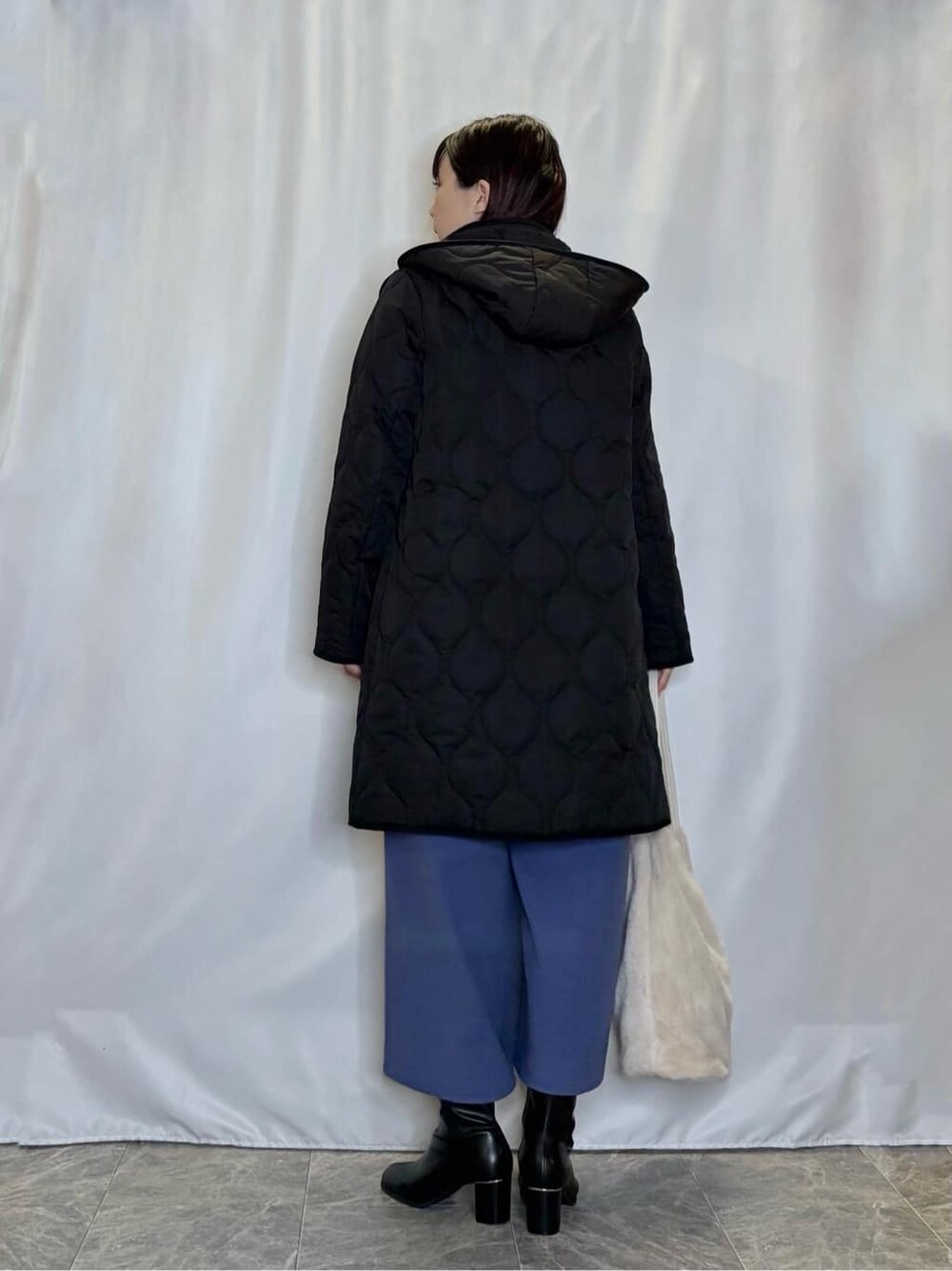 ブラック系のその他アウター、ホワイト系のニット/セーター、ブルー系のその他パンツを着用したレディースの冬コーディネートの3枚目の写真