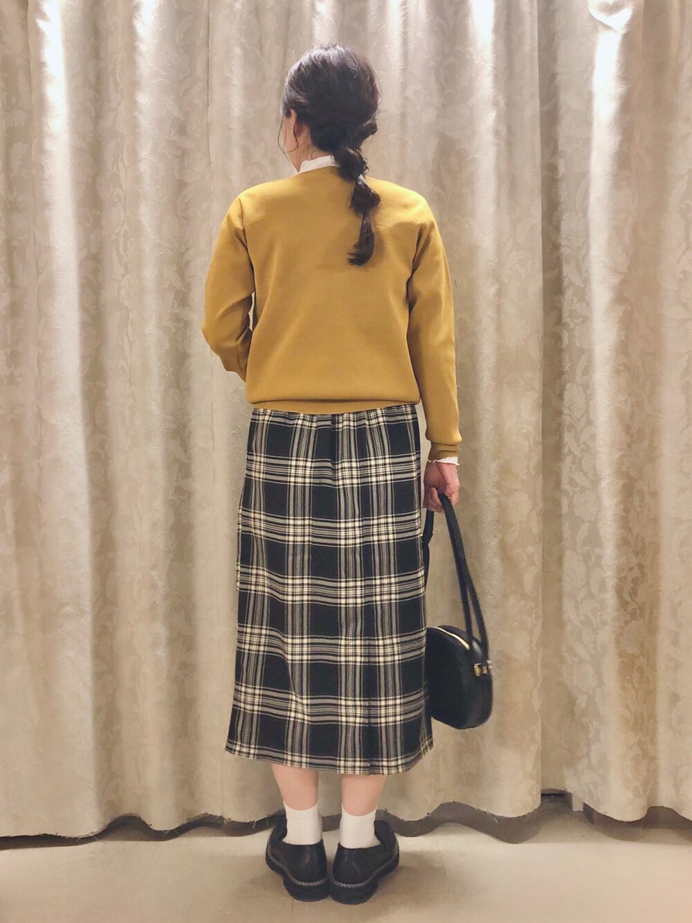 ブラック系のスカート、イエロー系のカーディガン/ボレロ、ホワイト系のTシャツ/カットソーを着用したレディースの秋コーディネートの3枚目の写真