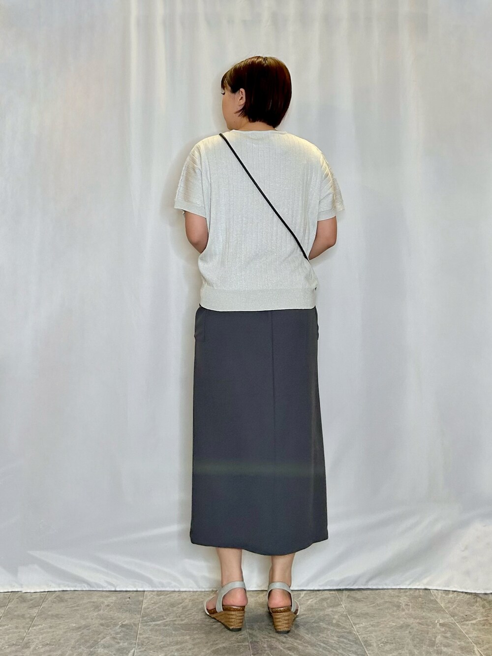 シルバー系のニット/セーター、グレー系のスカート、シルバー系のサンダルを着用したレディースの春コーディネートの3枚目の写真