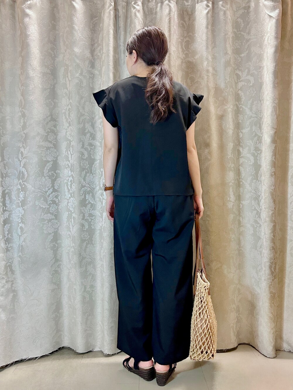 ブラウン系のトートバッグ、ブラック系のサンダル、ブラック系のシャツ/ブラウスを着用したレディースの夏コーディネートの3枚目の写真