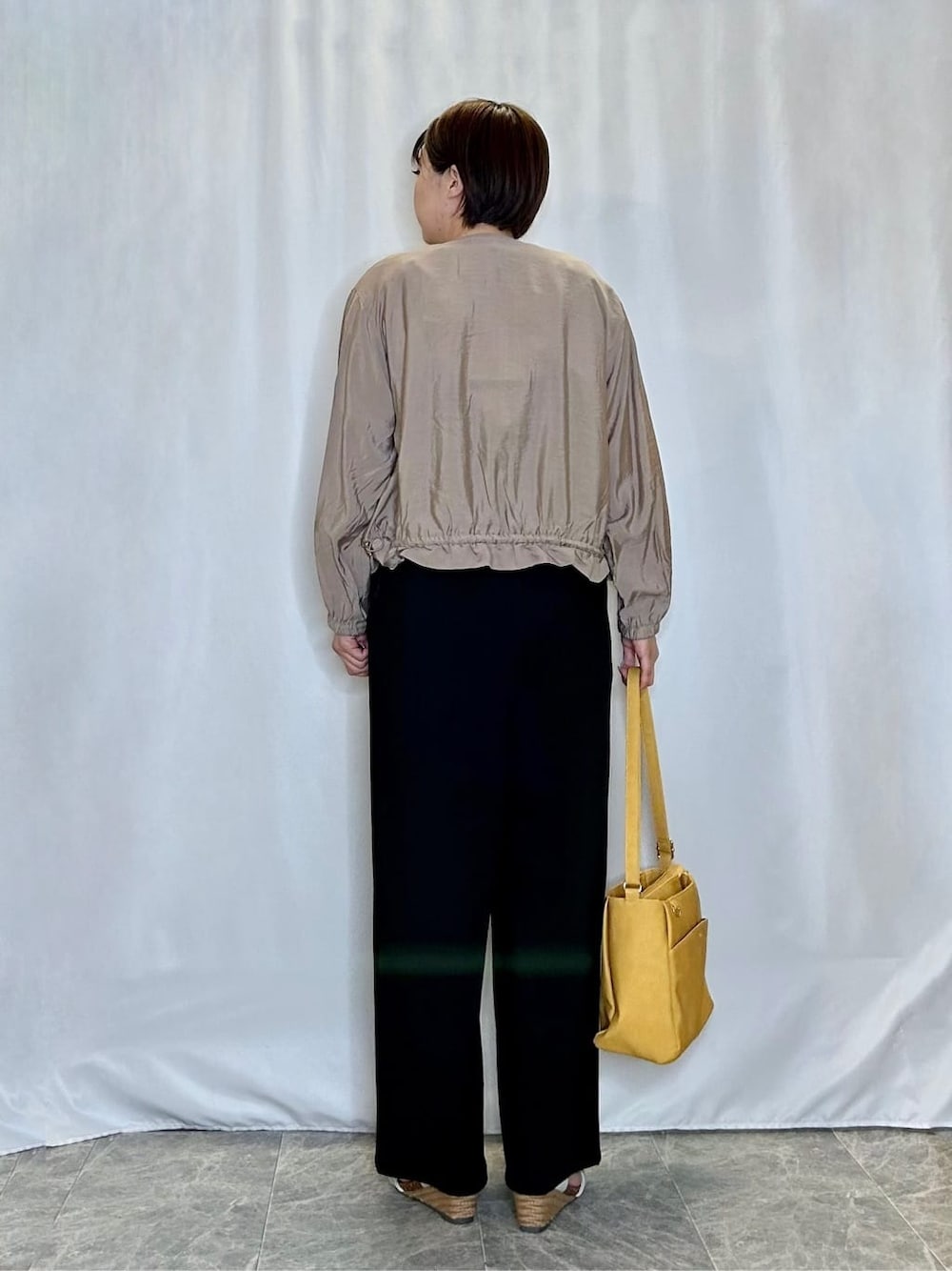 ベージュ系のブルゾン、ブラック系のサロペット/オーバーオール、ホワイト系のTシャツ/カットソーを着用したレディースの春コーディネートの3枚目の写真