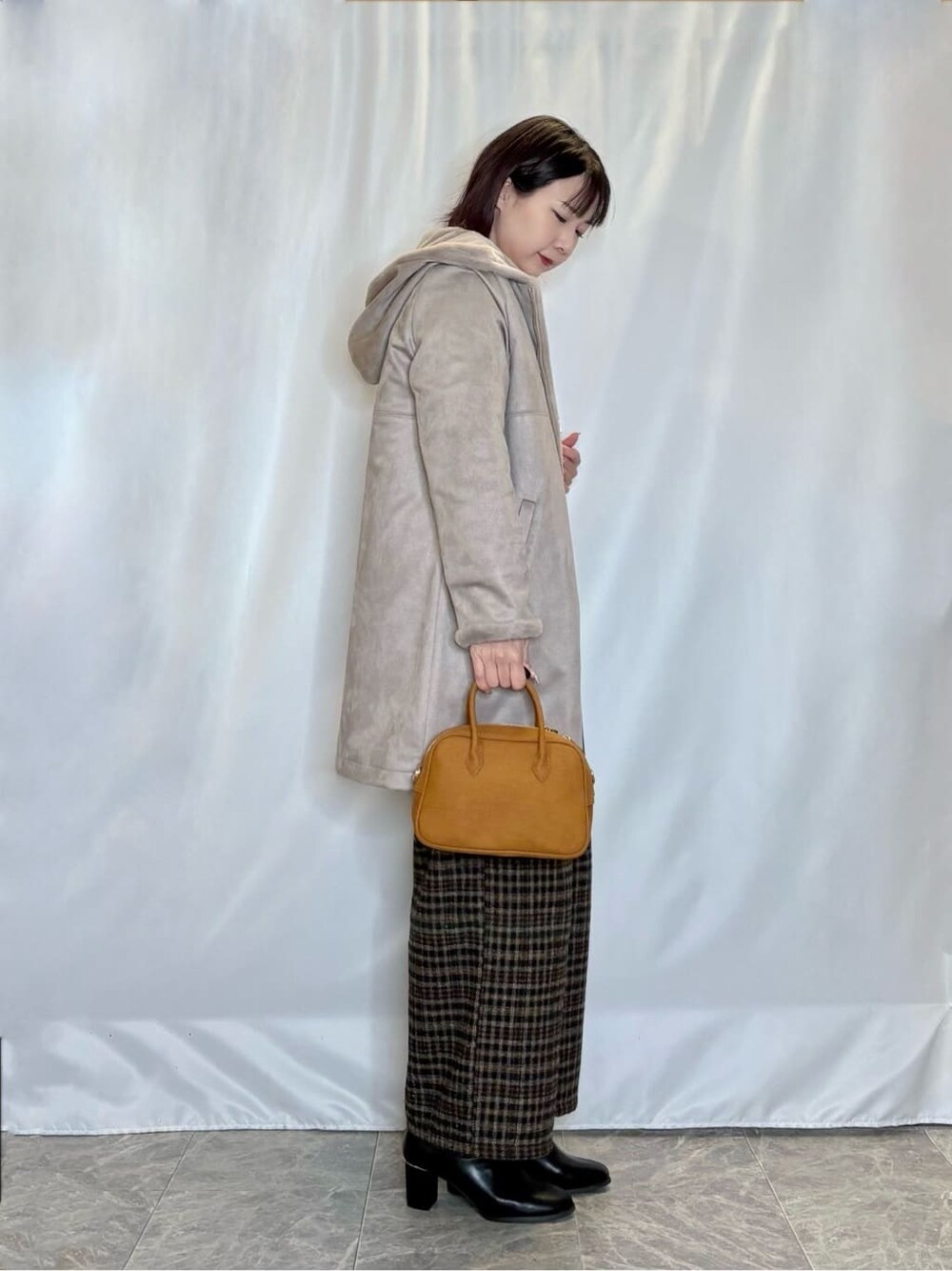 ブラウン系のその他アウター、オレンジ系のニット/セーター、ブラック系のその他パンツを着用したレディースの冬コーディネートの2枚目の写真