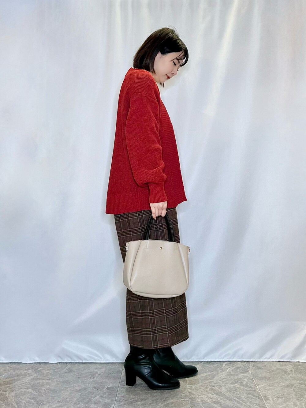 ブラック系のブーツ、ベージュ系のトートバッグ、レッド系のスカートを着用したレディースの冬コーディネートの2枚目の写真