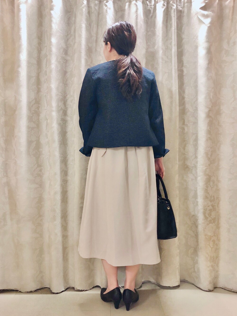 ブラック系のパンプス、ブラック系のトートバッグ、ホワイト系のシャツ/ブラウスを着用したレディースの春コーディネートの3枚目の写真