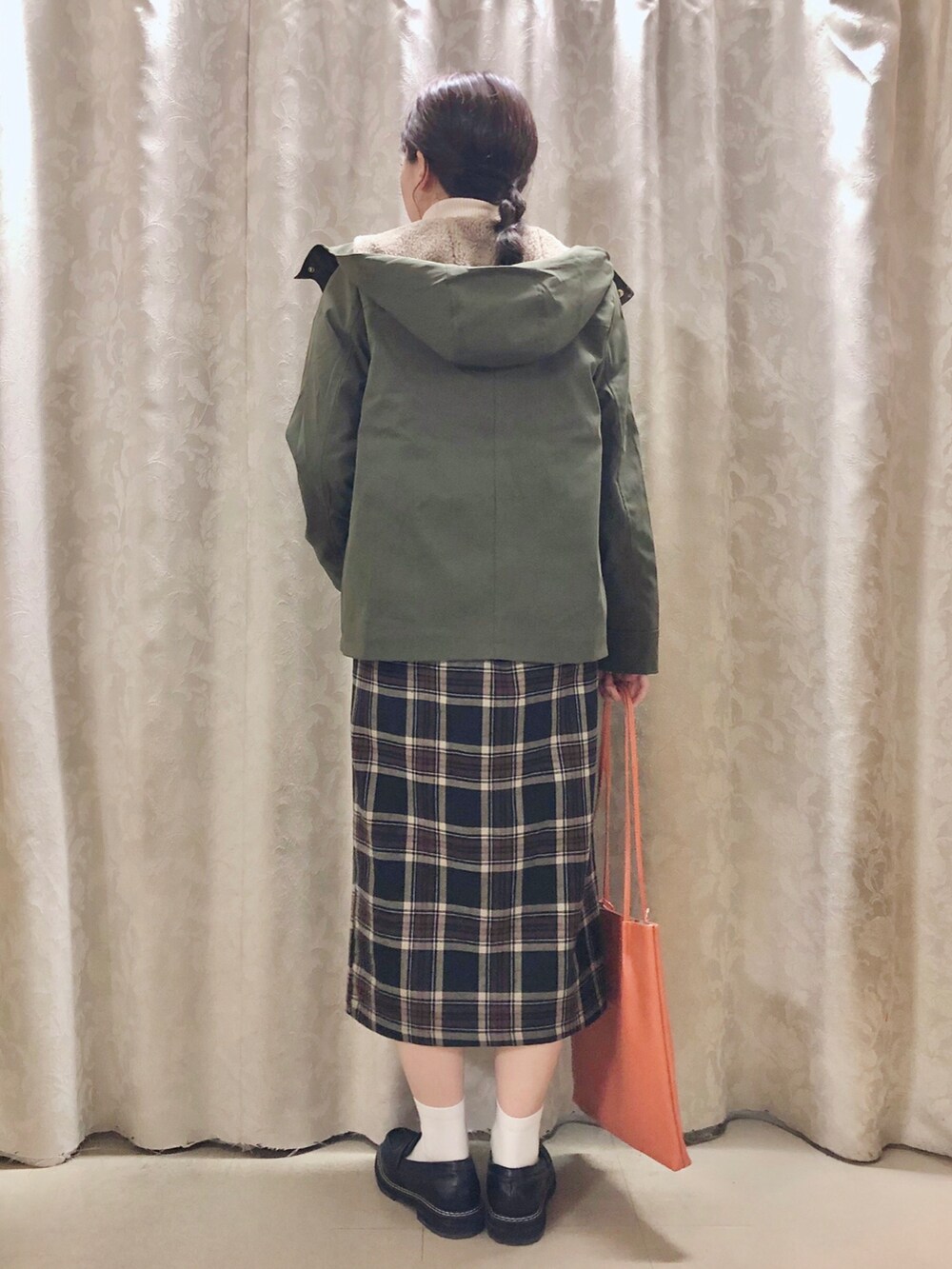 オレンジ系のトートバッグ、ブラック系のドレスシューズ、グリーン系のブルゾンを着用したレディースの秋コーディネートの3枚目の写真