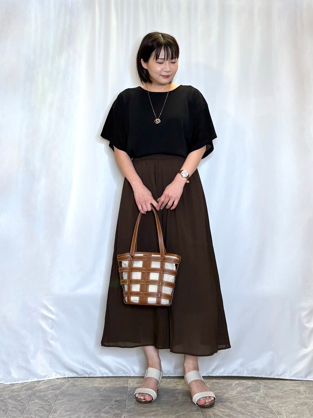 ブラック系のニット/セーター、ブラウン系のその他パンツ、ホワイト系のサンダルを着用したレディースの夏コーディネートの2枚目の写真