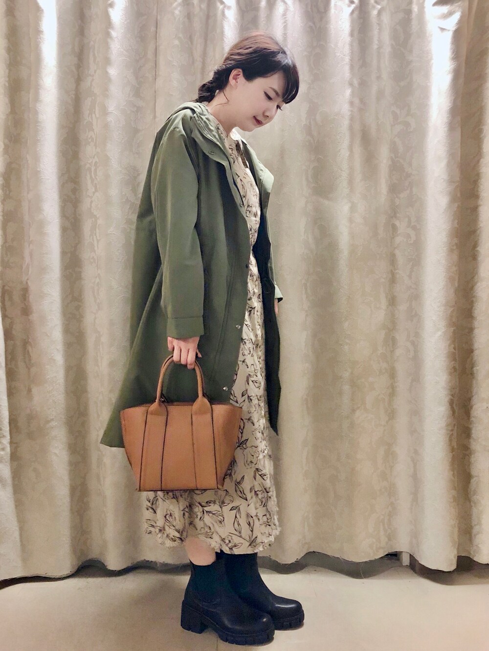 イエロー系のトートバッグ、ブラック系のブーツ、ベージュ系のワンピースを着用したレディースの秋コーディネートの2枚目の写真