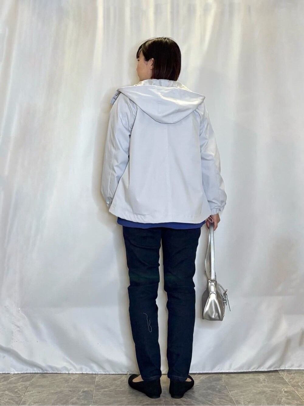 グレー系のブルゾン、パープル系のニット/セーター、ブルー系のデニムパンツを着用したレディースの春コーディネートの3枚目の写真
