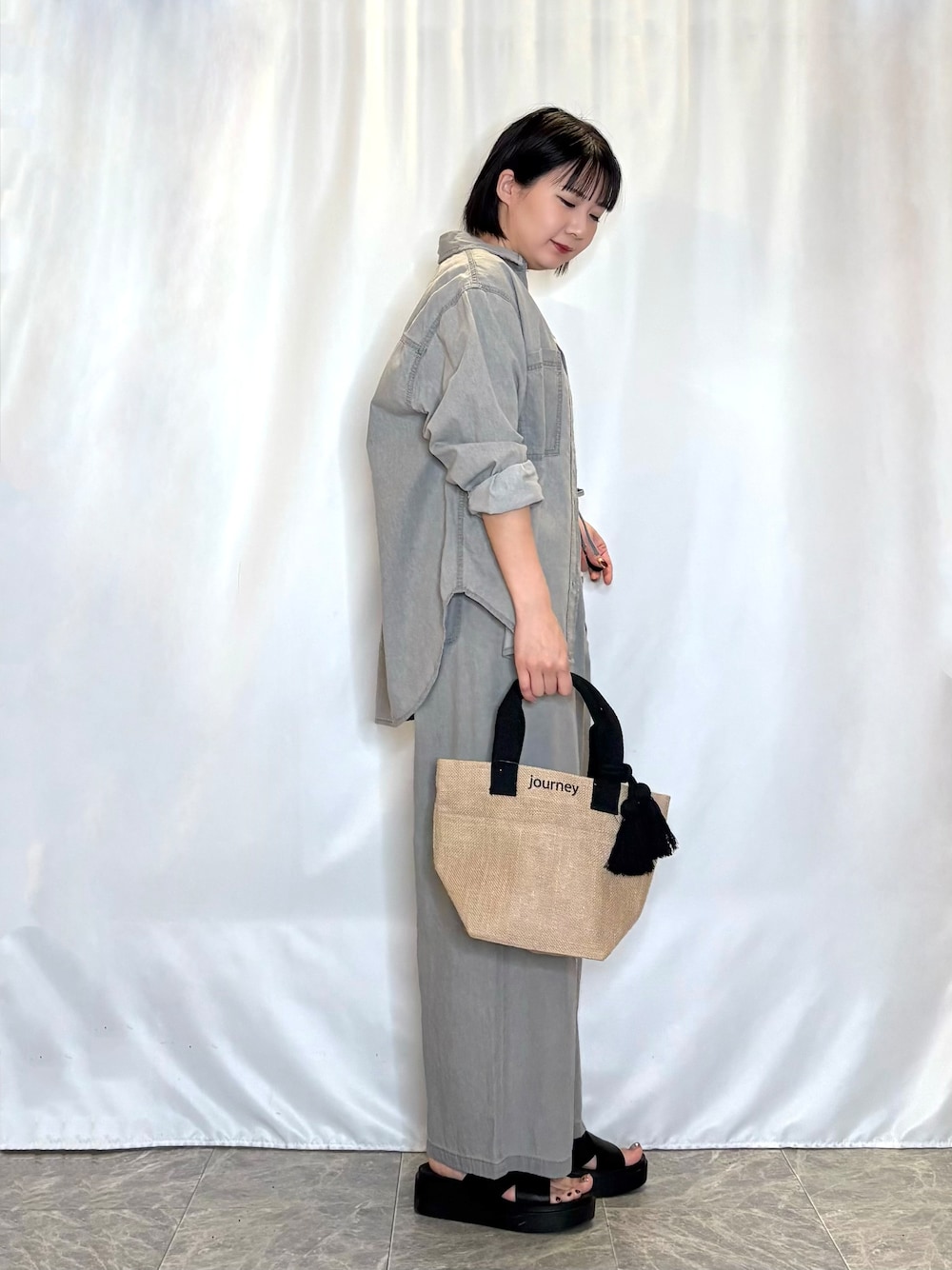 グレー系のデニムパンツ、グレー系のシャツ/ブラウス、ブラック系のトートバッグを着用したレディースの春コーディネートの2枚目の写真