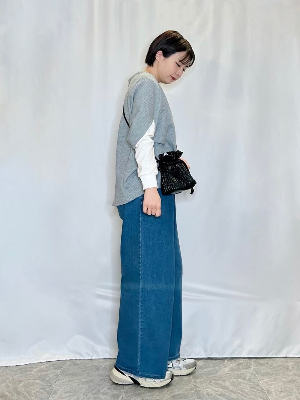 グレー系のその他トップス、ブルー系のデニムパンツ、ブラック系のショルダーバッグを着用したレディースの春コーディネートの2枚目の写真