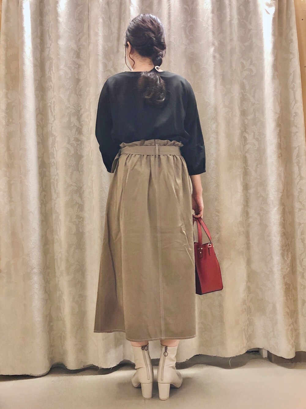 レッド系のショルダーバッグ、ホワイト系のブーツ、ベージュ系のスカートを着用したレディースの秋コーディネートの3枚目の写真