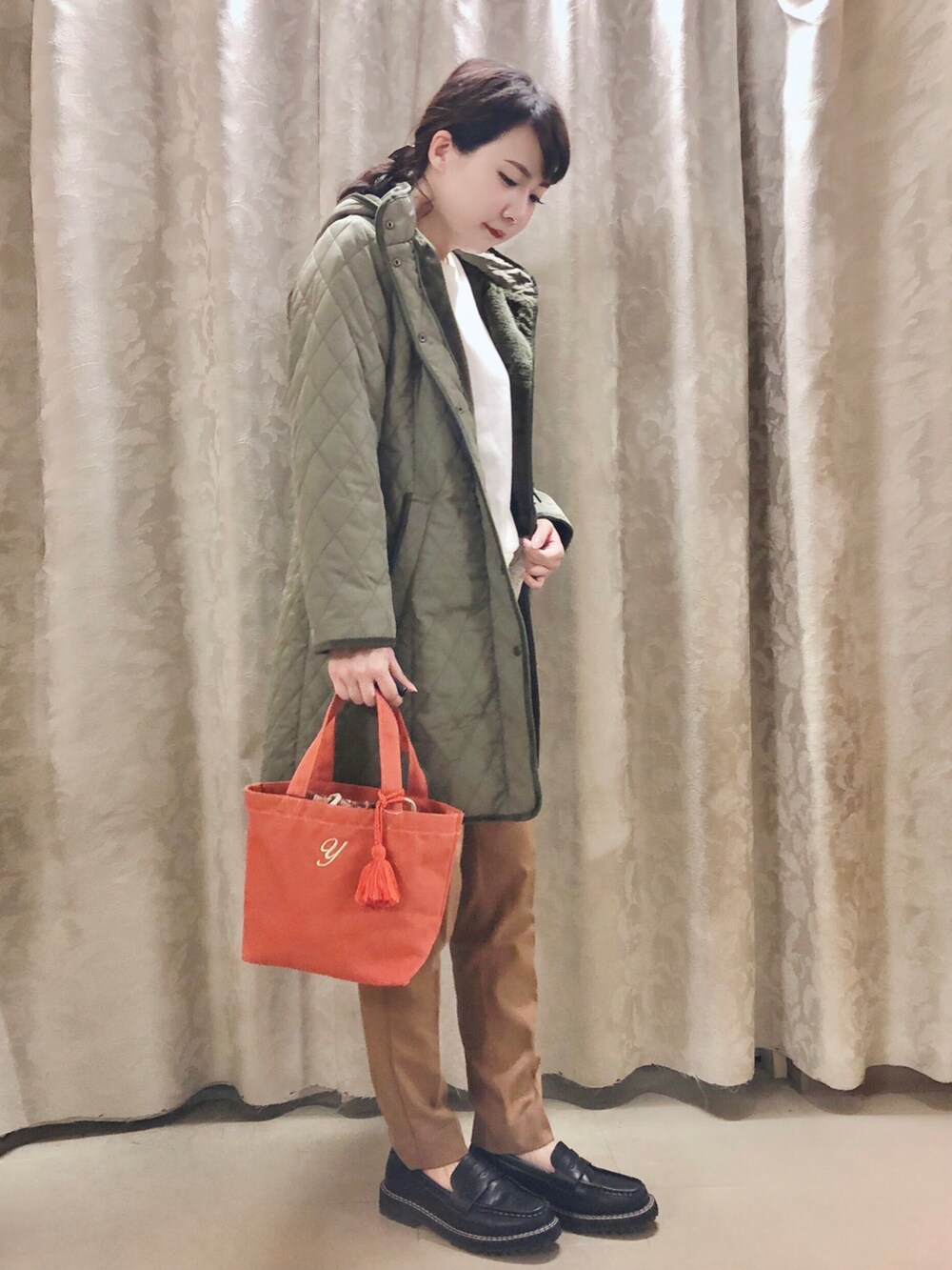 オレンジ系のトートバッグ、グリーン系のその他アウター、ホワイト系のスウェットを着用したレディースの秋コーディネートの2枚目の写真