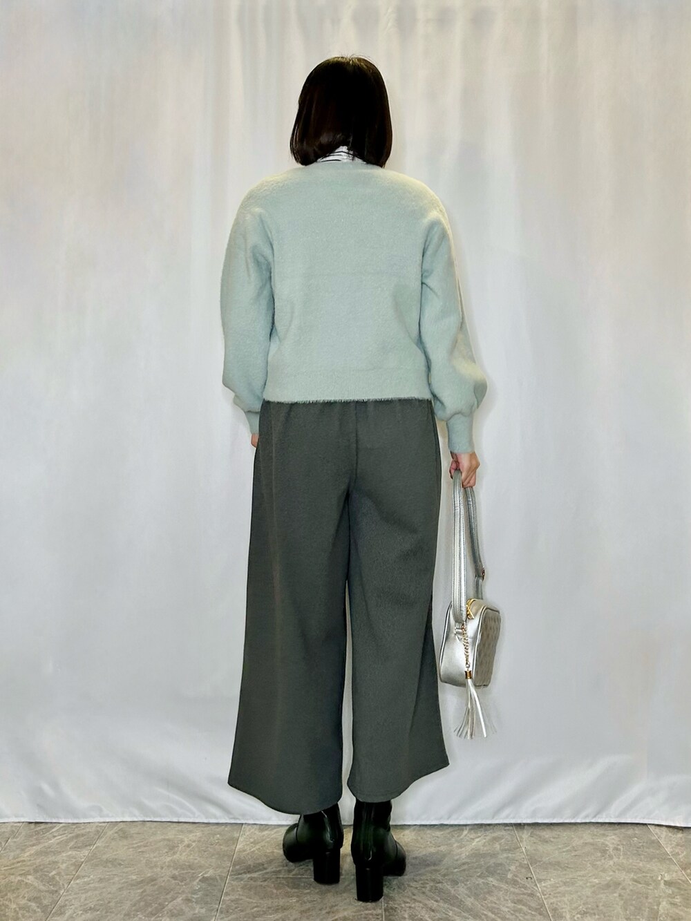 ホワイト系のTシャツ/カットソー、シルバー系のショルダーバッグ、ブラック系のブーツを着用したレディースの冬コーディネートの3枚目の写真