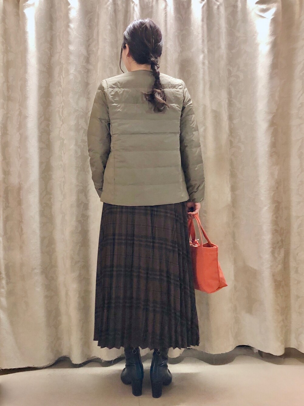 グリーン系のダウンジャケット/コート、ブラウン系のスカート、ブラック系のブーツを着用したレディースの秋コーディネートの3枚目の写真