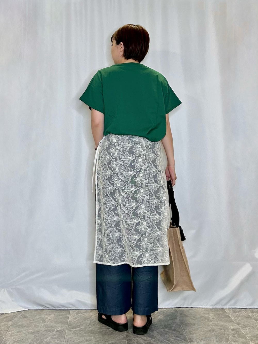 グリーン系のTシャツ/カットソー、ホワイト系のスカート、ブラック系のサンダルを着用したレディースの春コーディネートの3枚目の写真