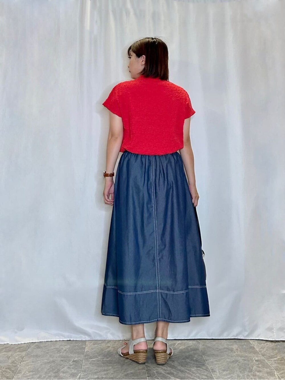 レッド系のTシャツ/カットソー、ブルー系のスカート、シルバー系のサンダルを着用したレディースの夏コーディネートの3枚目の写真