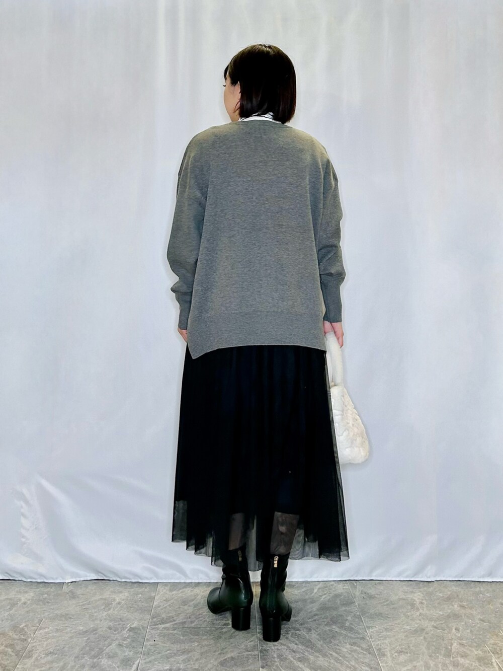 ベージュ系のトートバッグ、ブラック系のブーツ、グレー系のニット/セーターを着用したレディースの秋コーディネートの3枚目の写真