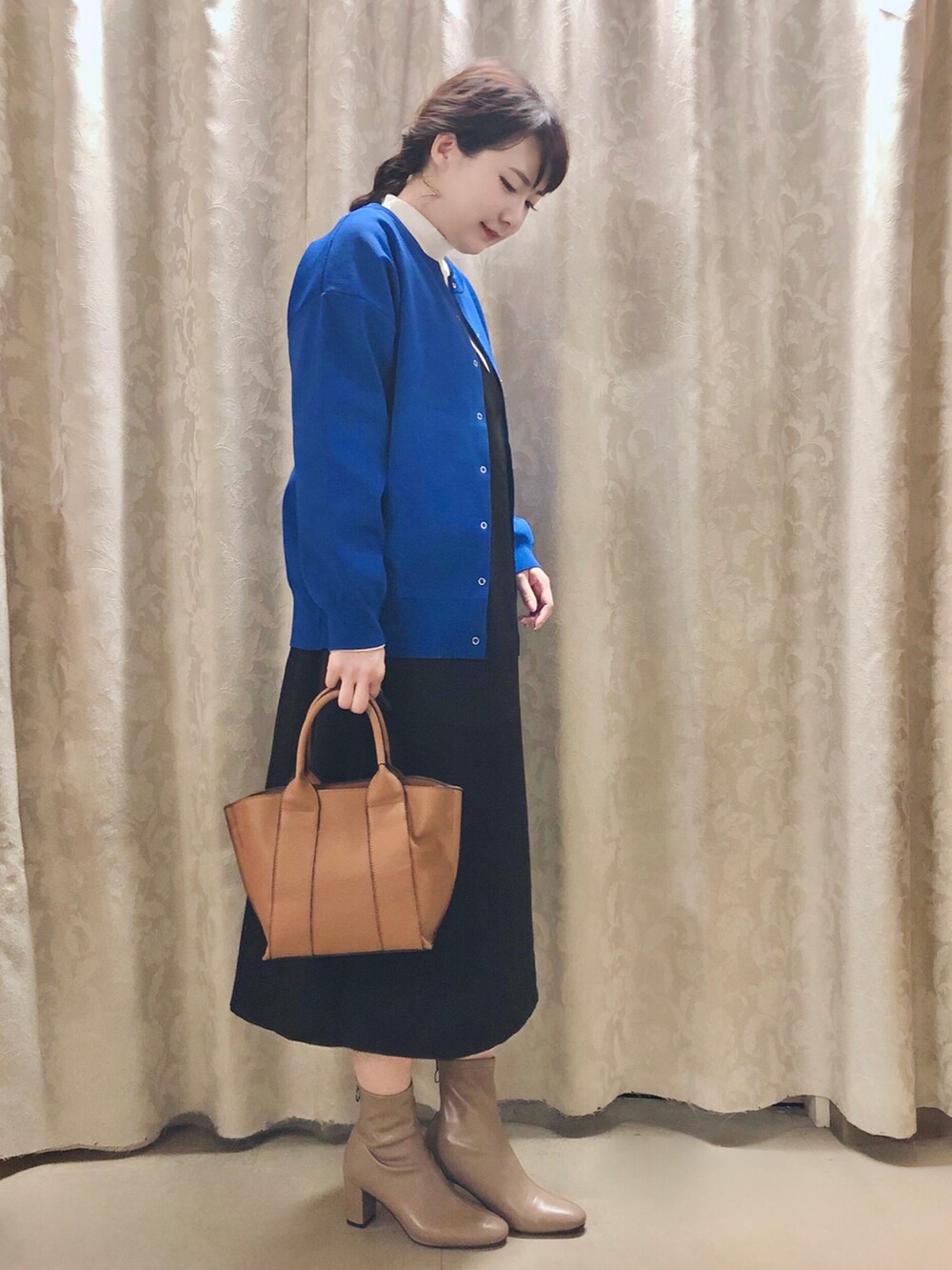 イエロー系のトートバッグ、ベージュ系のブーツ、ホワイト系のTシャツ/カットソーを着用したレディースの秋コーディネートの2枚目の写真