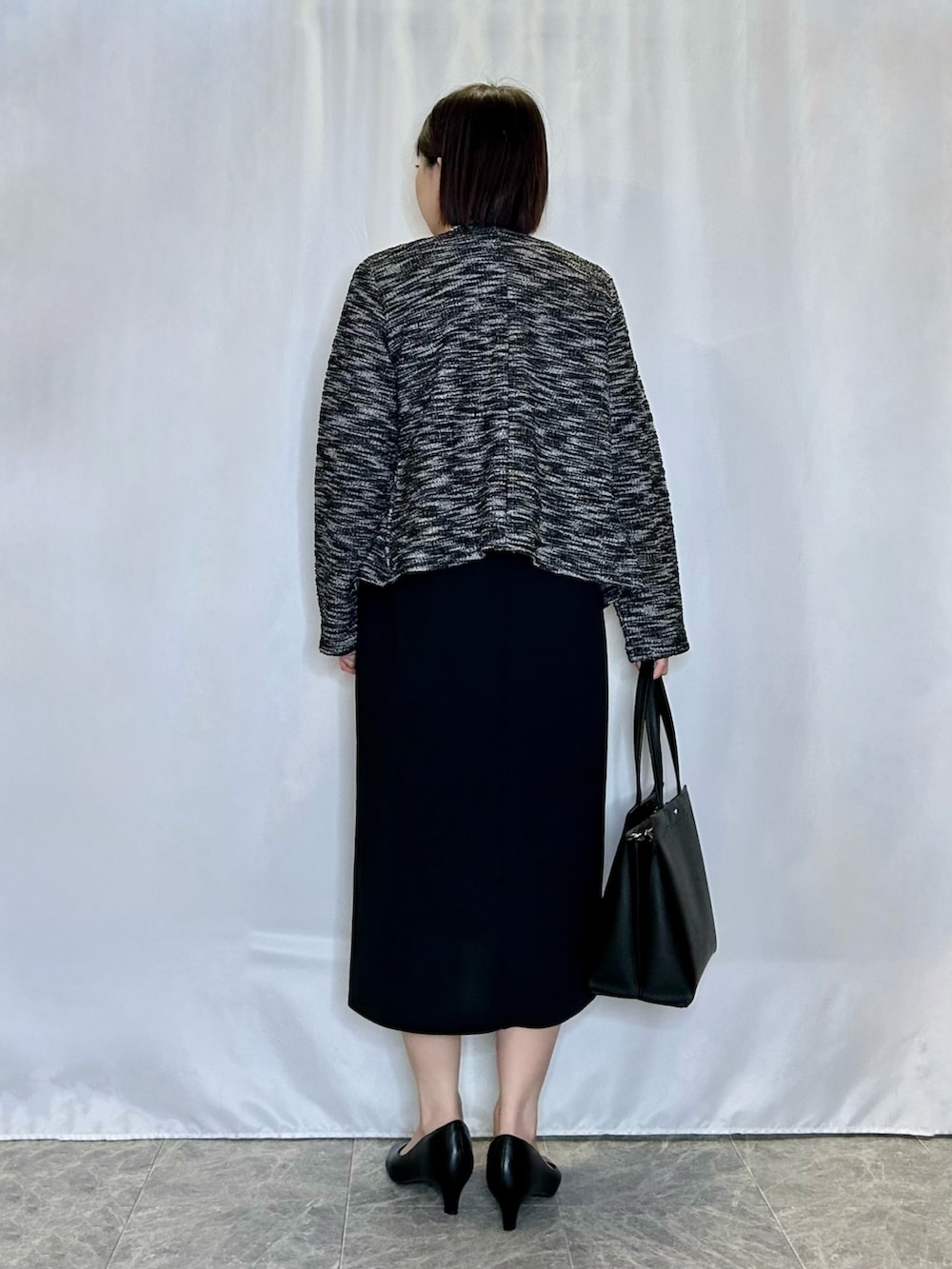 ブラック系のトートバッグ、ブラック系のパンプス、ブラック系のワンピースを着用したレディースの冬コーディネートの3枚目の写真