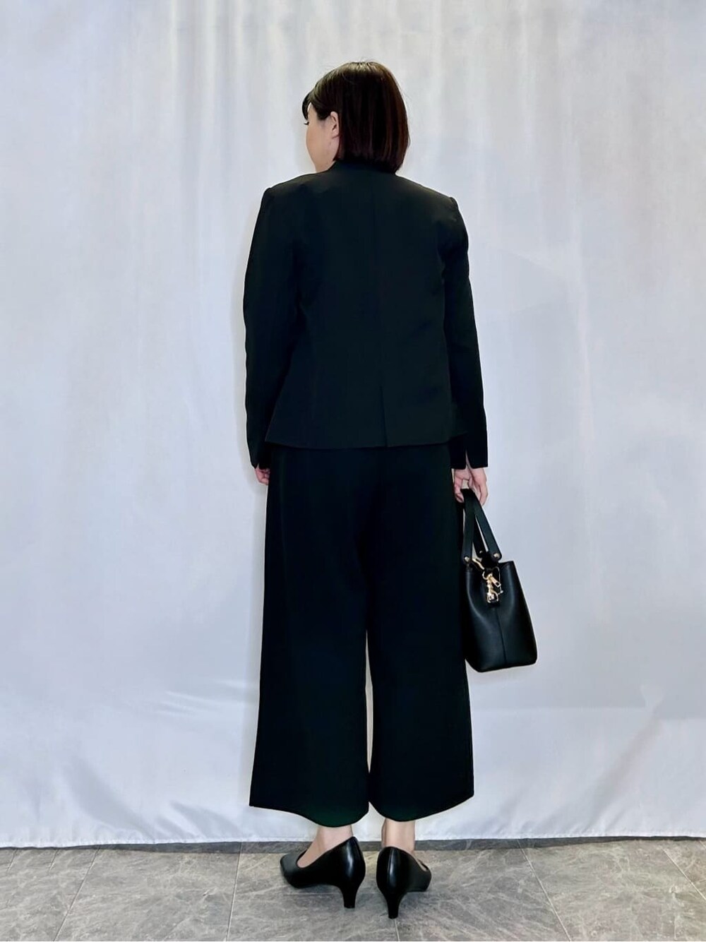 ブラック系のノーカラージャケット、ホワイト系のシャツ/ブラウス、ブラック系のその他パンツを着用したレディースの冬コーディネートの3枚目の写真