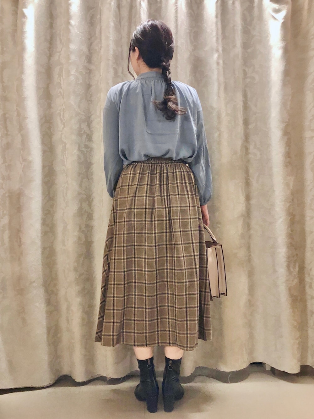 ベージュ系のスカート、グレー系のショルダーバッグ、ブラック系のブーツを着用したレディースの秋コーディネートの3枚目の写真