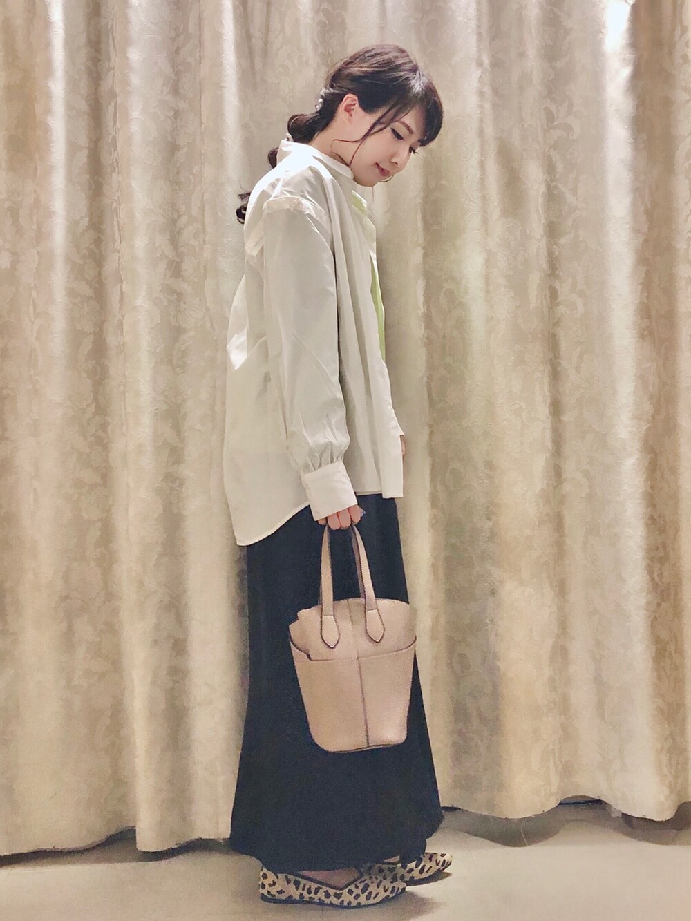 ブラック系のスカート、ベージュ系のトートバッグ、グリーン系のTシャツ/カットソーを着用したレディースの秋コーディネートの2枚目の写真