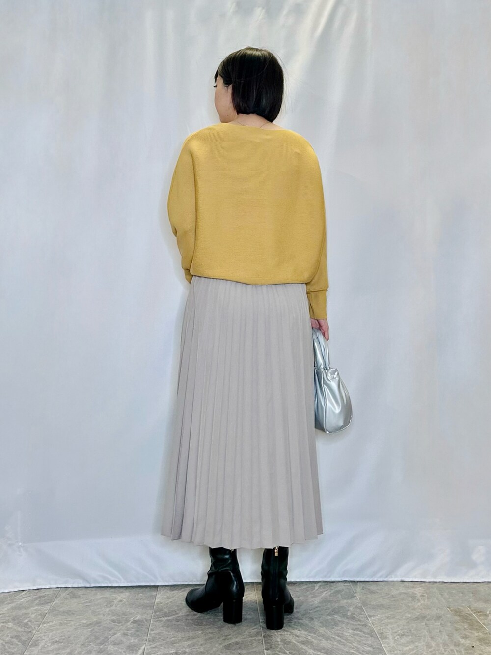 ブラック系のブーツ、シルバー系のトートバッグ、ベージュ系のスカートを着用したレディースの冬コーディネートの3枚目の写真