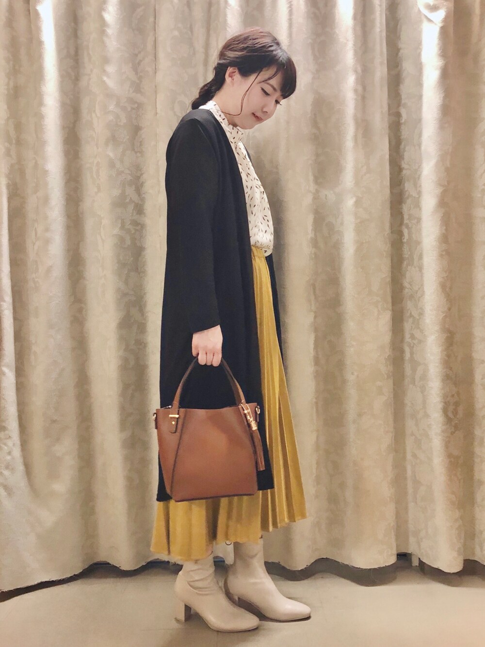 ホワイト系のシャツ/ブラウス、ブラック系のカーディガン/ボレロ、イエロー系のスカートを着用したレディースの秋コーディネートの2枚目の写真