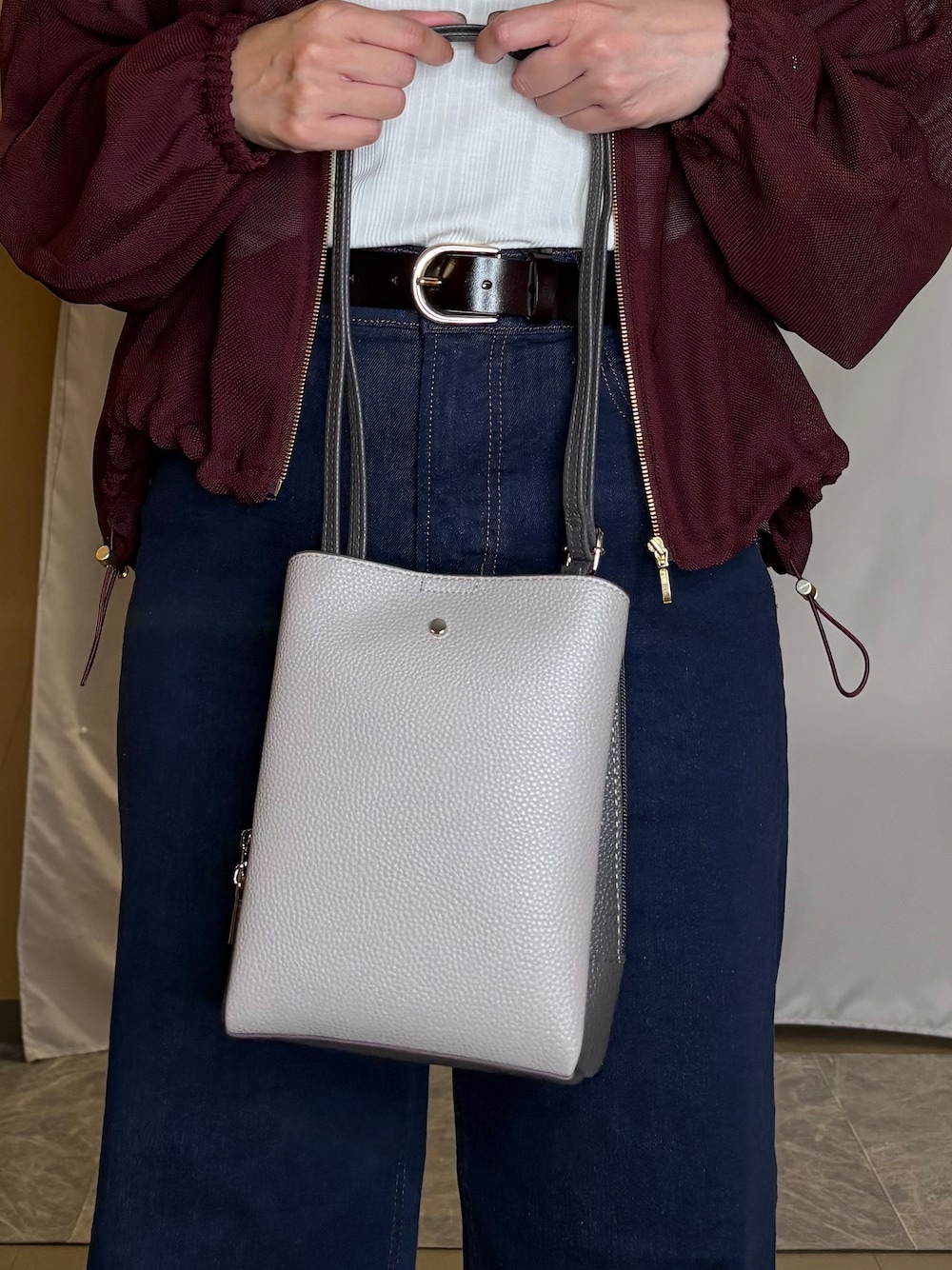 レッド系のブルゾン、ホワイト系のタンクトップ、ブルー系のデニムパンツを着用したレディースの秋コーディネートの4枚目の写真