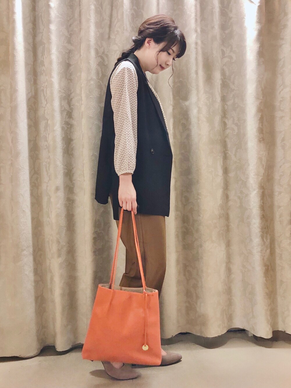 オレンジ系のトートバッグ、ベージュ系のパンプス、ベージュ系のパンツを着用したレディースの秋コーディネートの2枚目の写真