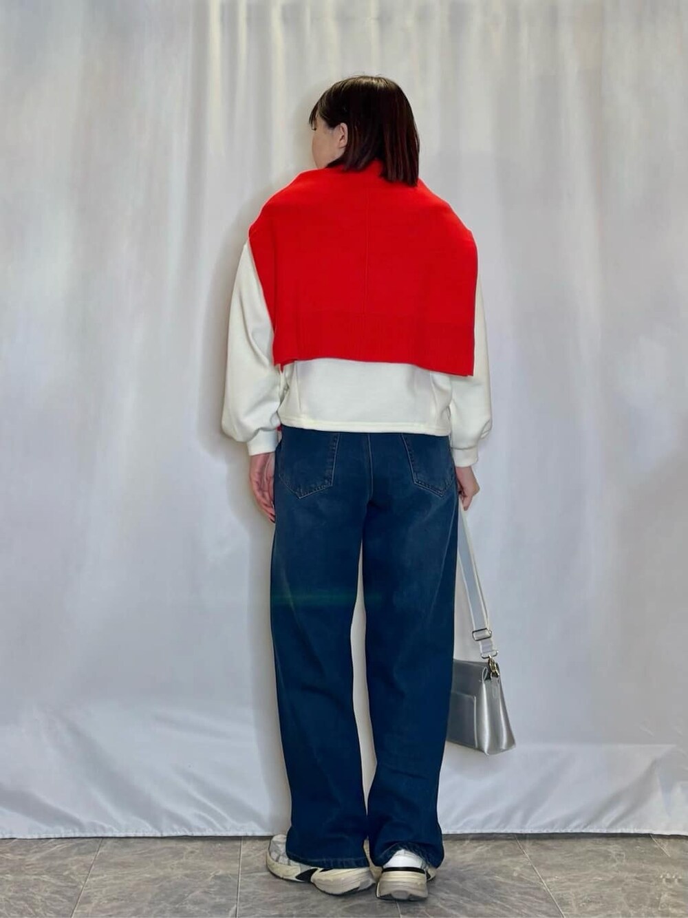 オレンジ系のニット/セーター、ホワイト系のTシャツ/カットソー、ブルー系のデニムパンツを着用したレディースの冬コーディネートの3枚目の写真