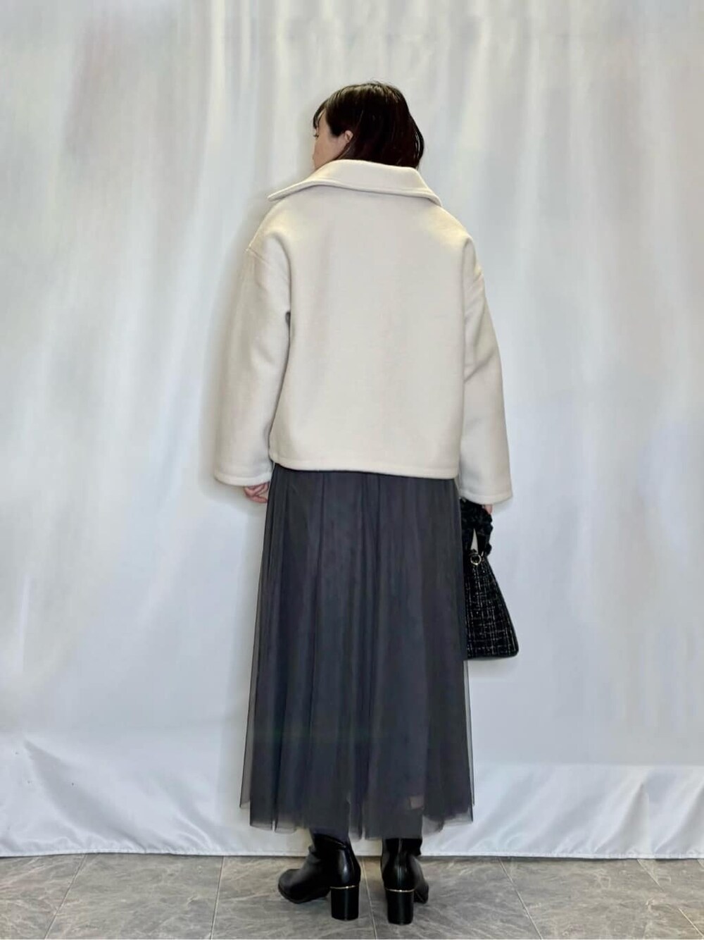 ホワイト系のブルゾン、ピンク系のニット/セーター、グレー系のスカートを着用したレディースの冬コーディネートの3枚目の写真