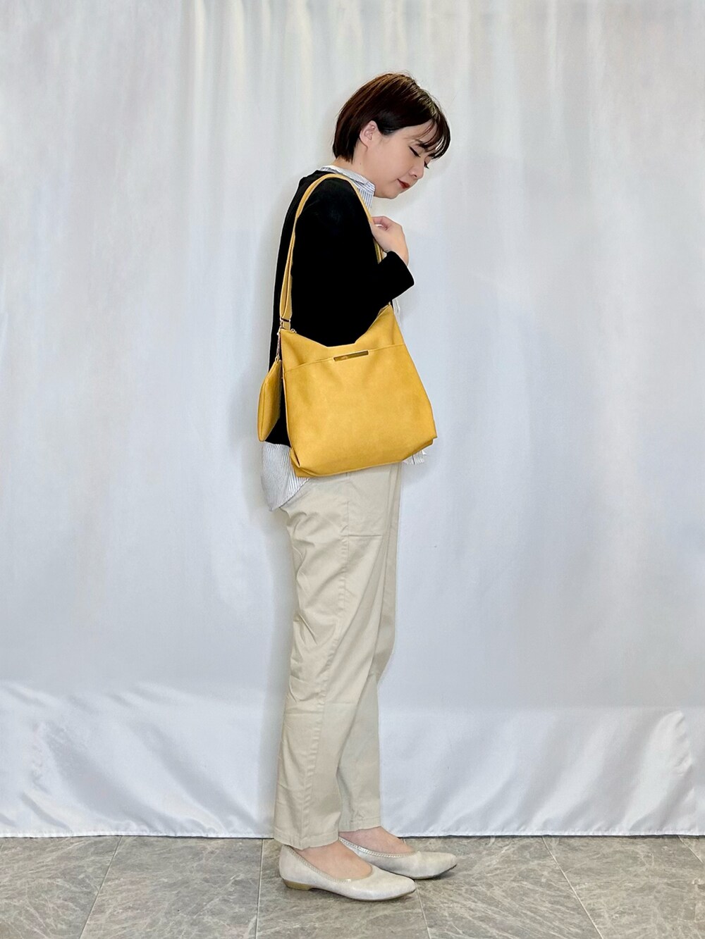 ゴールド系のその他シューズ、ベージュ系のその他パンツ、イエロー系のショルダーバッグを着用したレディースの春コーディネートの2枚目の写真