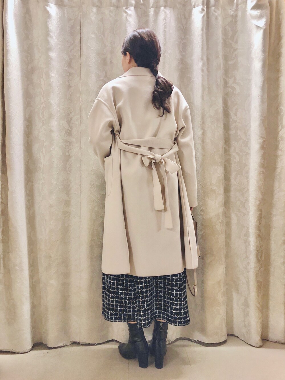 ベージュ系のショルダーバッグ、ブラック系のブーツ、ベージュ系のチェスターコートを着用したレディースの冬コーディネートの3枚目の写真